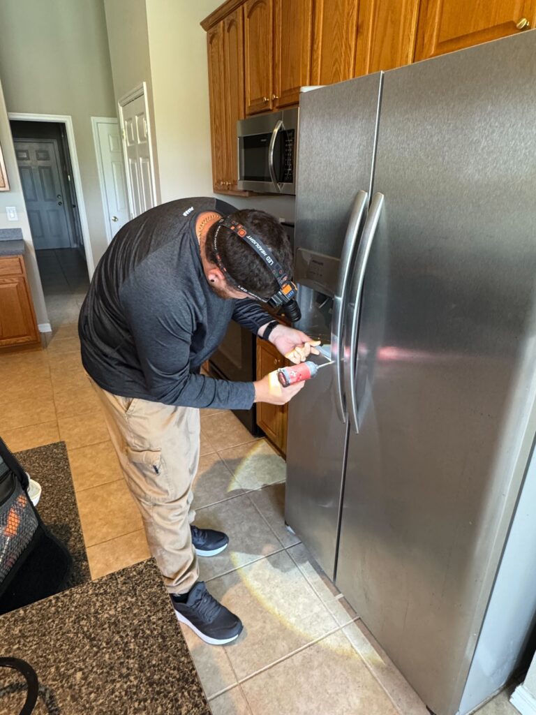 Tampa Bay Appliance Technician is working on side by side refrigerator's dispenser