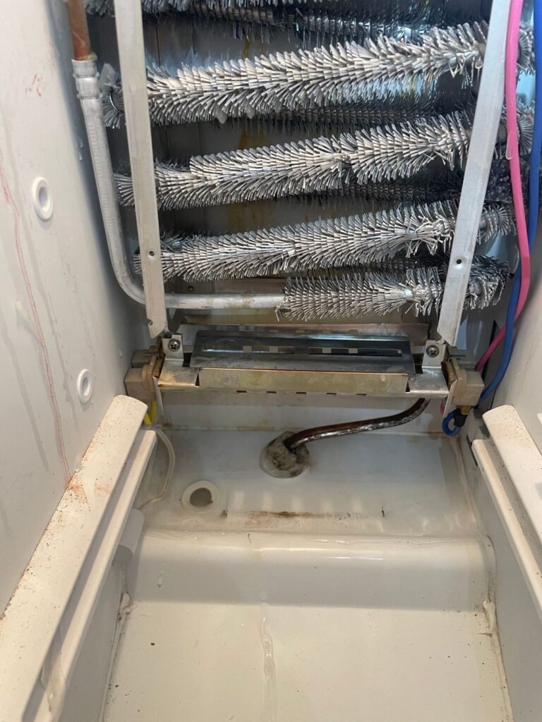 Frosted evaporator coil and drain trough in a side-by-side freezer