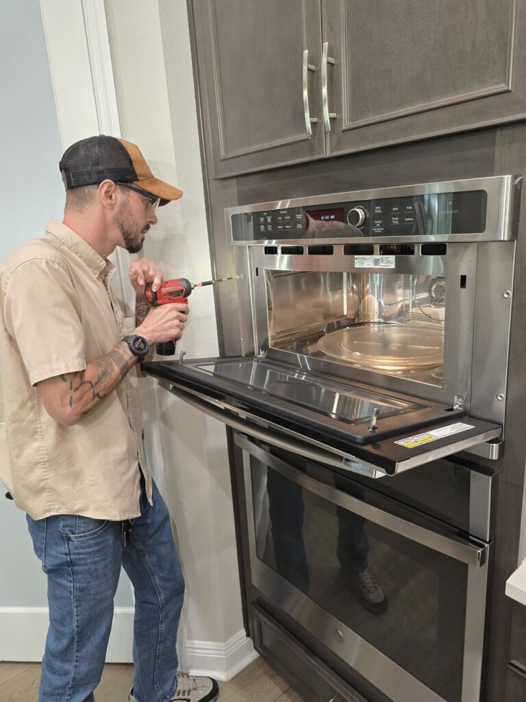 Technician working on a built-in microwave above a wall oven